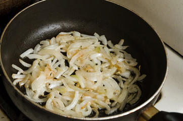Onion is fried in a pan