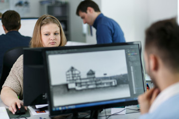 Look from behind the laptop on a blonde lady working at the comp