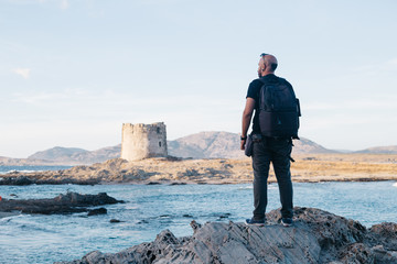  filtered back view of man standing at the seaside watching Stintino panorama