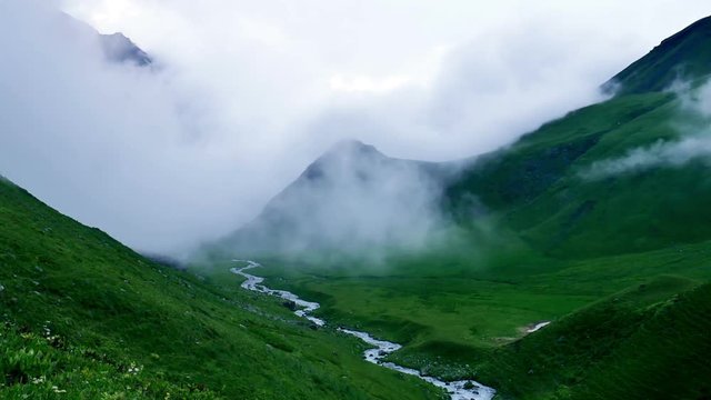 Timelapse of storm clouds fill the valley and greatly reduce visibility in high mountain green hills