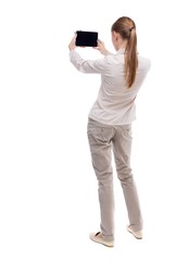 back view of standing young beautiful  girl with tablet computer in the hands of. girl  watching. Rear view people collection.  backside view of person.  Isolated over white background. A girl in a