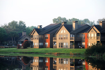 apartment buildings reflecting in tranquil lake in morning sunlight