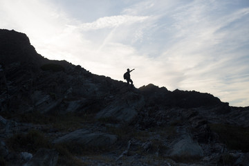 Back light silhouette of a man standing on a hill, overlooking,