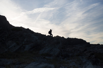 Back light silhouette of a man standing on a hill, overlooking,