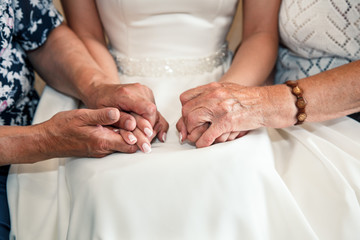 Bride and grandmother hold hands on wedding day