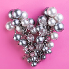Pearls in a heart shape on a pink background