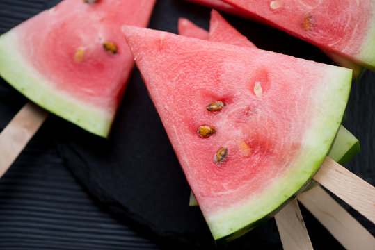 Close-up of ripe watermelon slices on sticks, above view