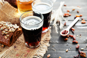 
summer and autumn cooling drink , kvass or  dark beer with honey , raisins and rye bread on a wooden background