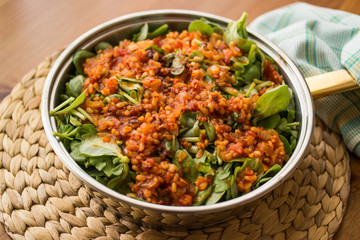 Purslane food with tomato sauce in a pan on a wicker.