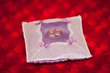 Golden wedding rings on decorated little purple pillow. Marriage concept