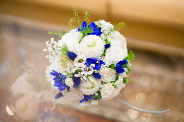 Blue and white wedding bouquet of roses on glass table