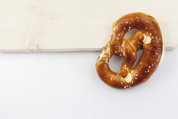 Eine Laugenbrezel liegt auf einem Holzbrett