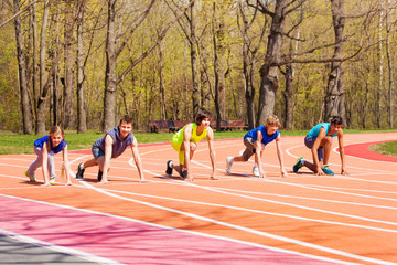 Five teens standing on starting position at track