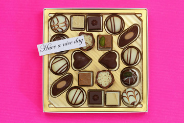 Have a nice day card with box of assorted chocolates on pink background
