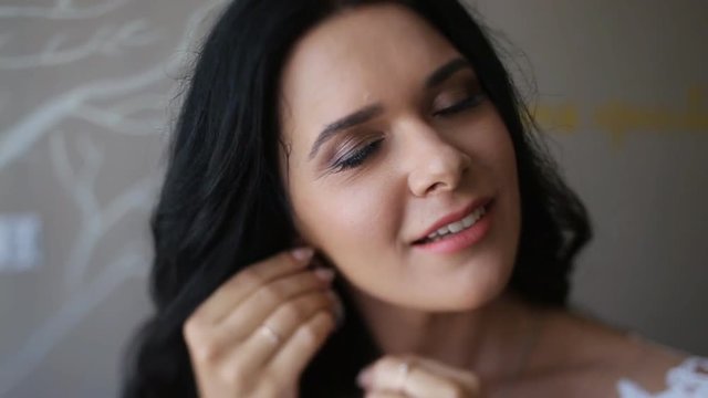 Beautiful gorgeous brunette bride in the morning. Posing anf putting on luxury earrings in the morning