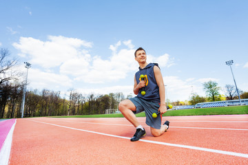 Fototapeta premium Picture of sporty boy with dumbbells in stadium