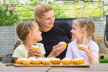 Mother and two daughters sitting at the table with Easter cupcakes in his hands