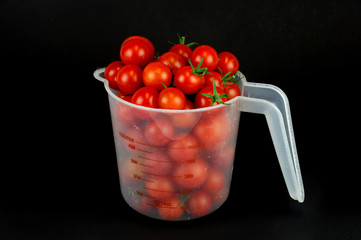 cherry tomato in the measuring cup isolated on black background