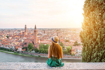 Woman enjoying beautiful view on Verona city in Italy on the sunset. Verona is famous city of love in the north of Italy. - obrazy, fototapety, plakaty