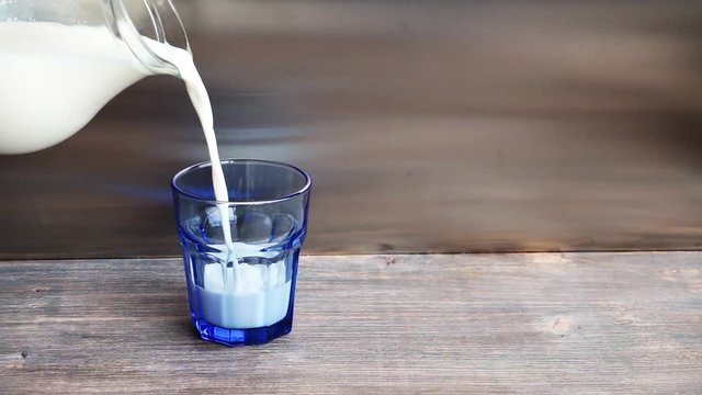 Pouring fresh milk into a blue glass. 