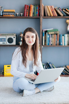 Happy woman with laptop on living room floor