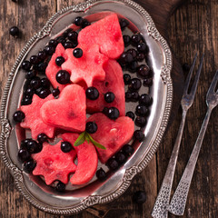 Summer fruit salad of watermelon and berries. Slices of watermelon in the shape of a star,heart,moon .wooden background