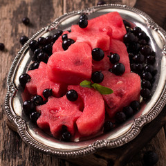 Summer fruit salad of watermelon and berries. Slices of watermelon in the shape of a star,heart,moon .wooden background