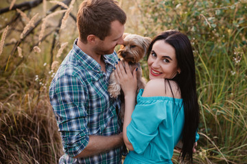 Young happy attractive couple posing with their dog - yorkshire terrier on nature,love,lifestyle,relationship