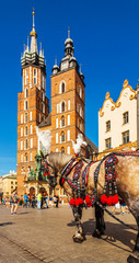 Fototapeta na wymiar Church of St. Mary in the main Market Square with beautifully decorated horse in the foreground. Basilica Mariacka. Krakow. Poland.