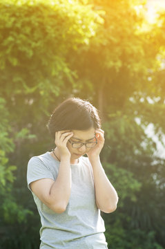Asian glasses woman having headache while workout at the park.