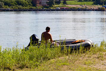Fisherman in a boat on the bank of  wide river