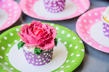 Rose cupcake with butter cream icing on grey background