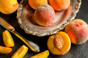 Peaches on a dark background. Whole and sliced juicy peaches.