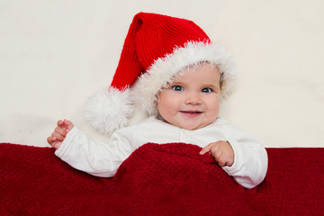 Photos of young baby in a Santa Claus hat  on white blanke