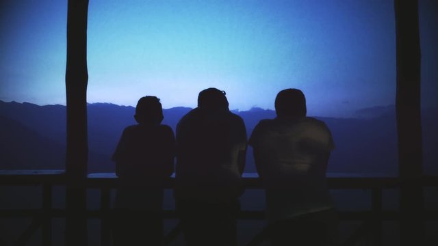 Silhouette of friends on a gazebo high on the mountains at dusk. 4k