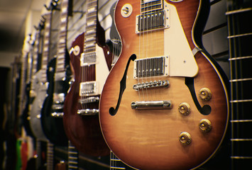 Reihe von Gitarren auf dem Display zum Verkauf hängen in einem Musikgeschäft - Vintage Instagram gefiltert.