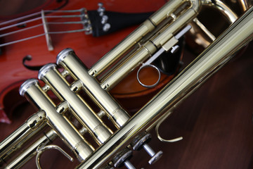 Detail close up of a trumpet and violin still life on a wood surface.