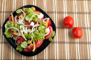 Aerial view of one portion of vegetable salad on a plate of blac