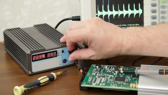 Engineer's hand  is tuning the knob of power supply unit