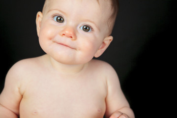 Sweet little boy sitting on studio black background
