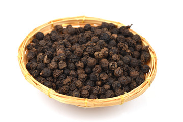 Black pepper, spices, medicinal properties in a basket on a white background.