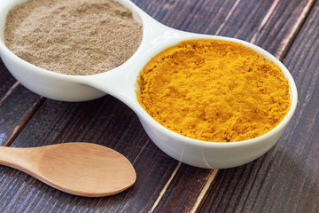Turmeric and black pepper in white ceramic bowl on wooden background. Ingredients for golden paste. Top view with copy space