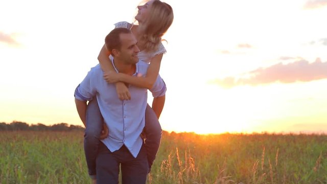 Beautiful Young Couple in Love twirls in a field at sunset