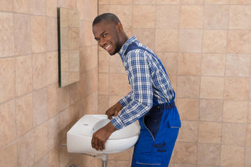 Male Plumber Fixing Sink In Bathroom