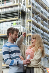 Couple with keys on front of new modern house