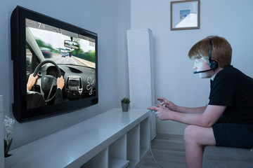Fototapeta na wymiar Boy Playing Car Game On Television