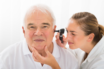 Doctor Looking At Patient's Ear Through Otoscope