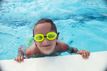 Naklejka premium Cheerful boy in goggles in swimming pool 