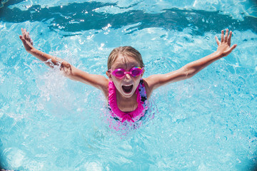 Cheerful girl  in goggles in swimming pool