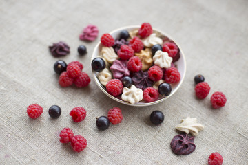 Colorful berries and pastila in a plate, raspberries and currant, rustic style